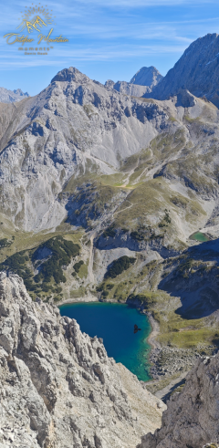 Berge, Gebirgsee Blick auf einen Gebirgssee umgeben von steilen Felsen und grünen Wiesen.