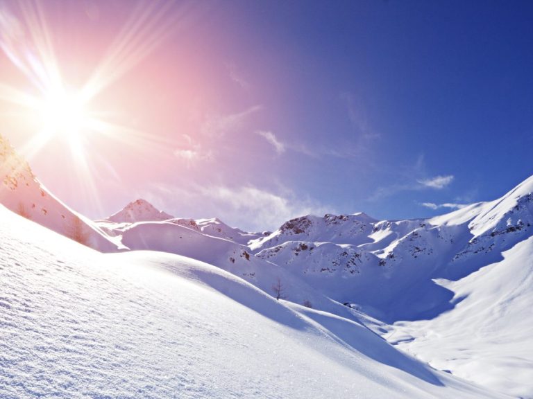 Berge mit Schnee Helle Sonneneinstrahlung auf schneebedeckten Bergen unter klarem Himmel.
